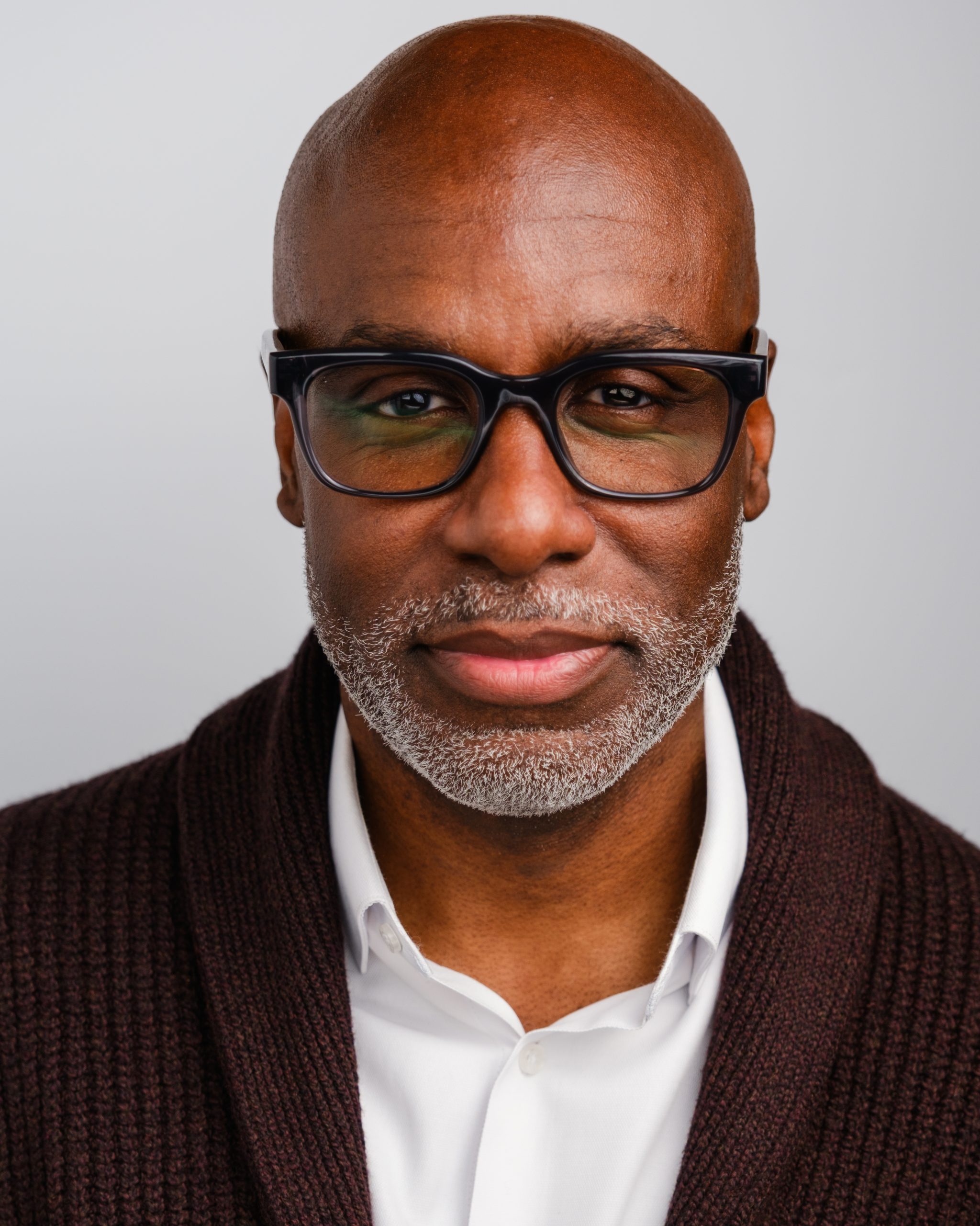 Darrell Brown Headshot in Brown Cardigan with White Shirt and Glasses